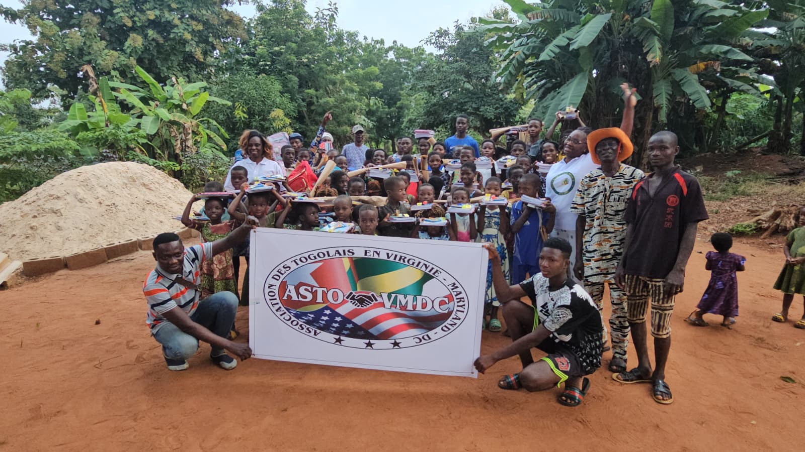 ASTO-VMDC members with children holding school supplies and the association banner in Togo